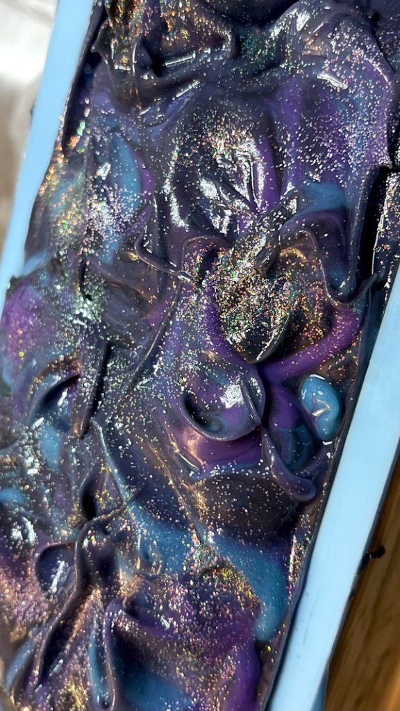 A close up of the purple and blue paint on a painting.