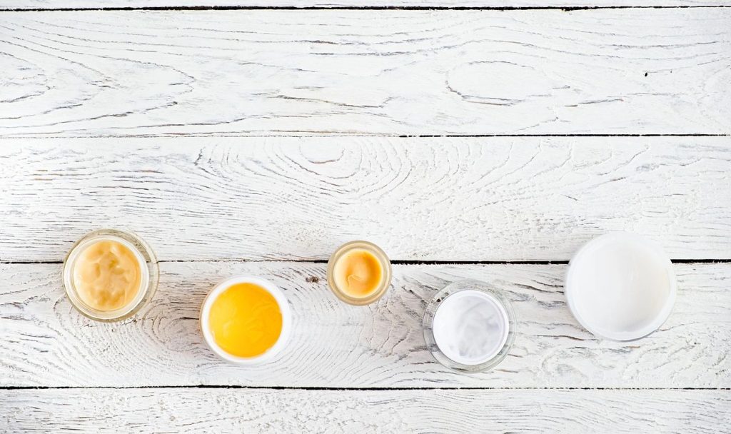 A white table with cups of orange juice and milk.