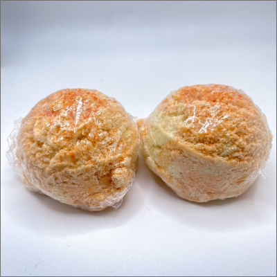 Two orange balls of bread wrapped in plastic.