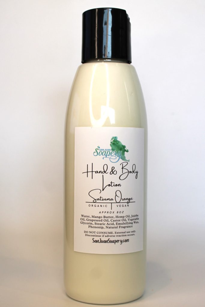 A bottle of hand and body lotion with a green plant on it.