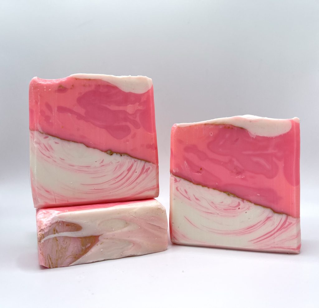 Three pink and white soap bars on a table.