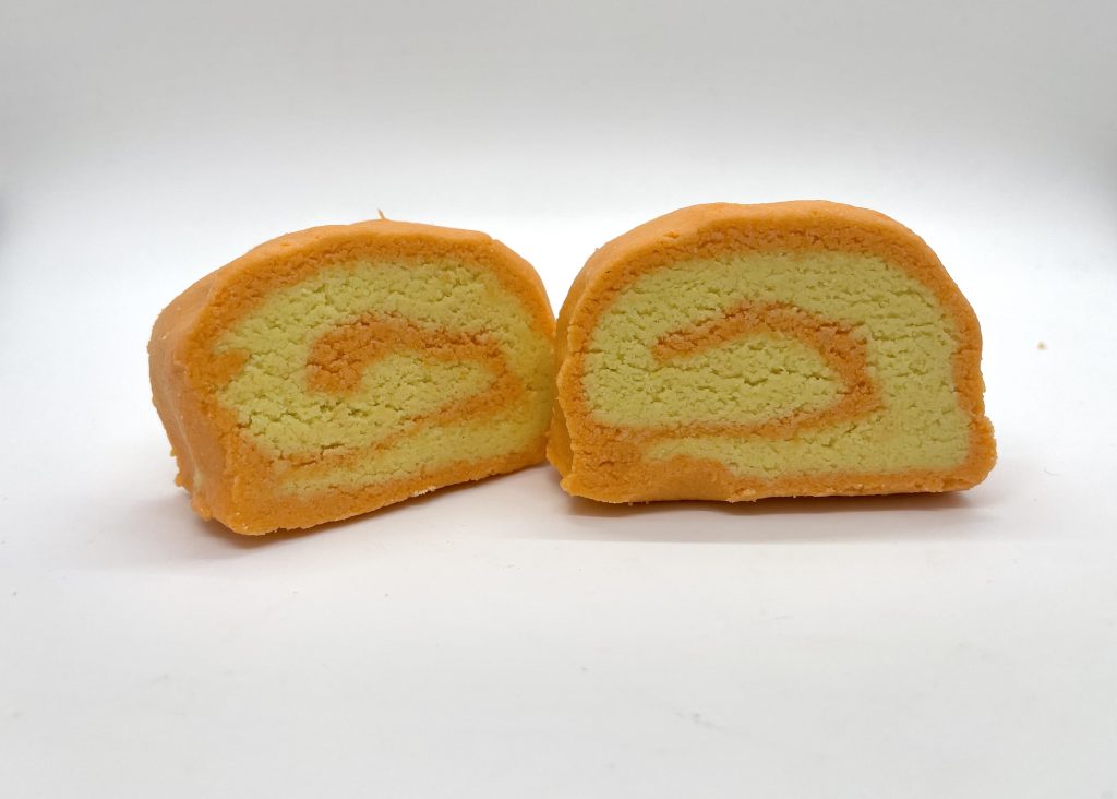 Two orange and yellow cakes are sitting on a table.