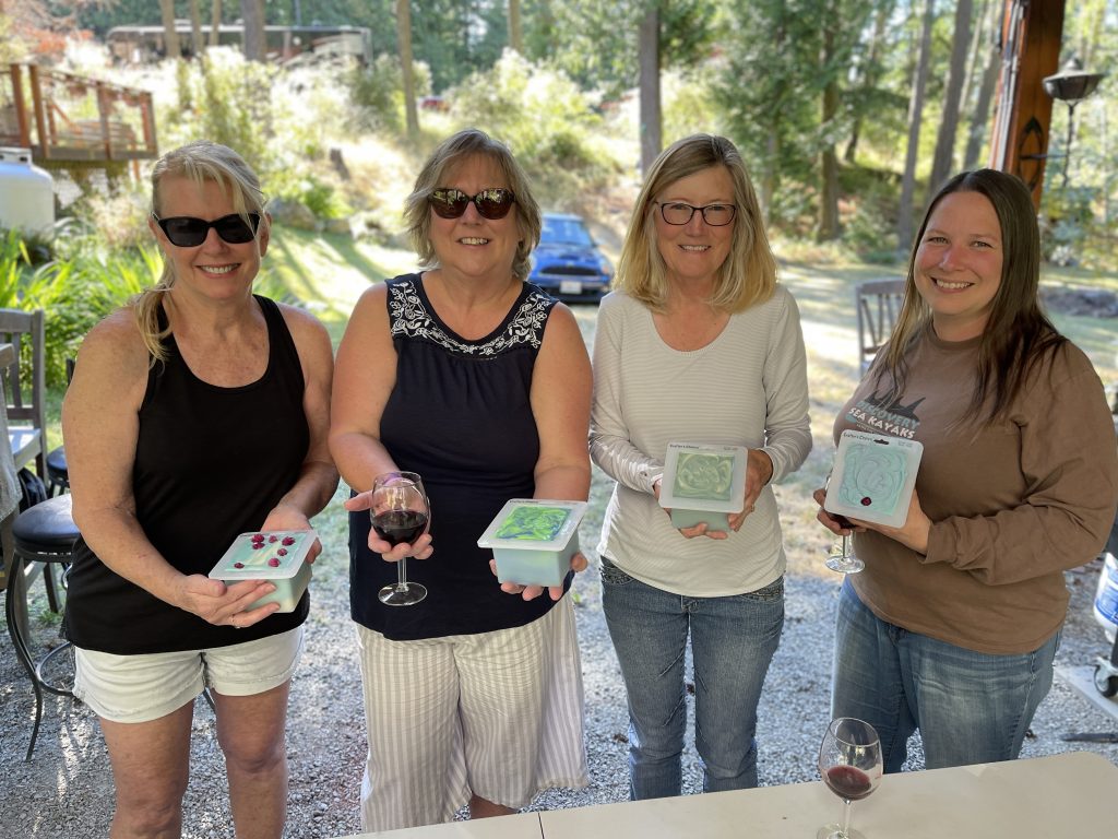 Four women holding boxes of wine and a glass.