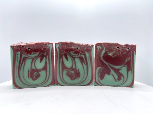 Three bars of soap with a red swirl on them.