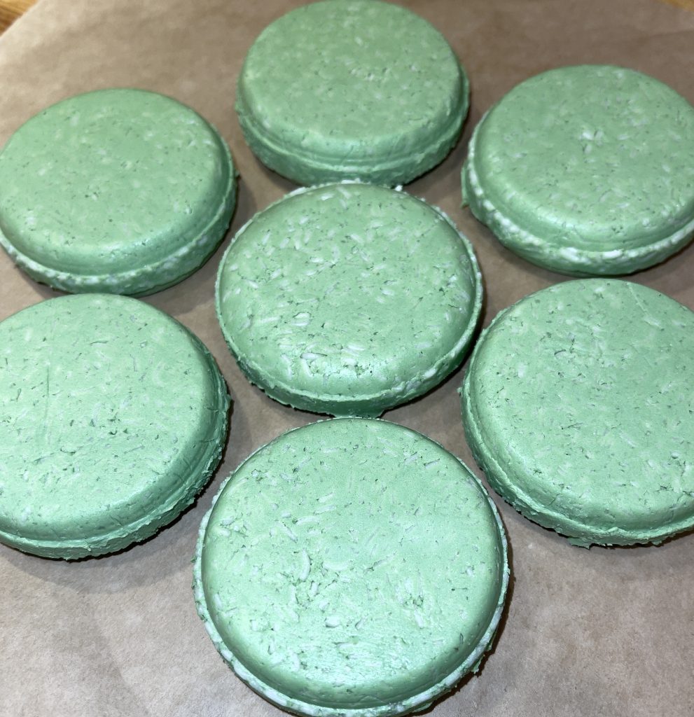 A group of green macarons sitting on top of a table.