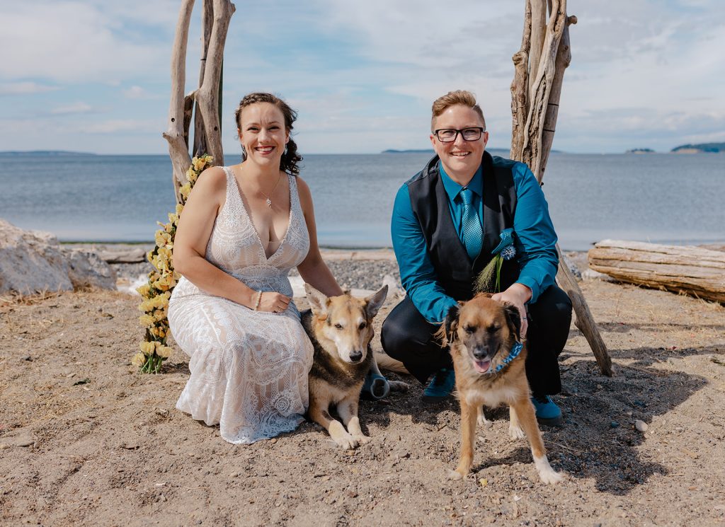 Two people and a dog sitting on the beach