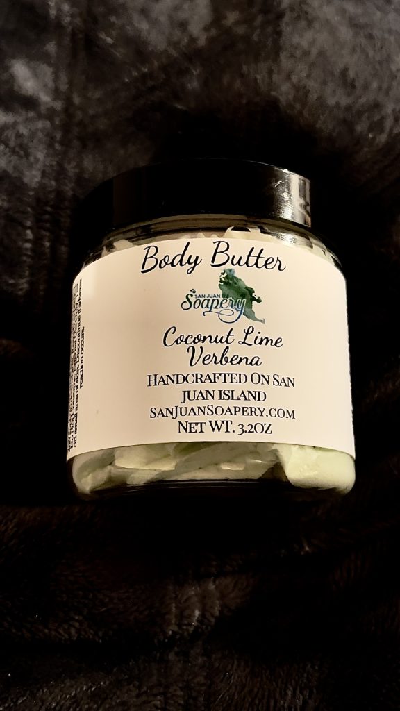 A jar of body butter with a green leaf on it.