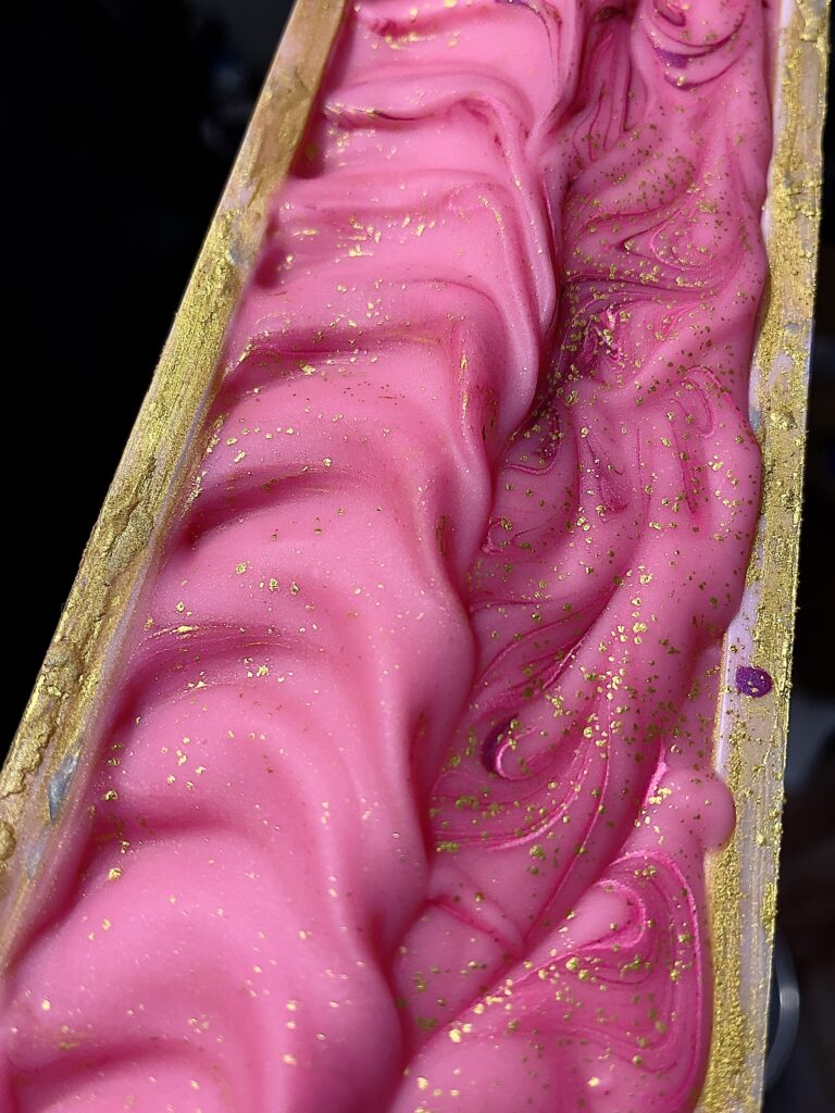 A pink liquid in a wooden box with gold sparkles.