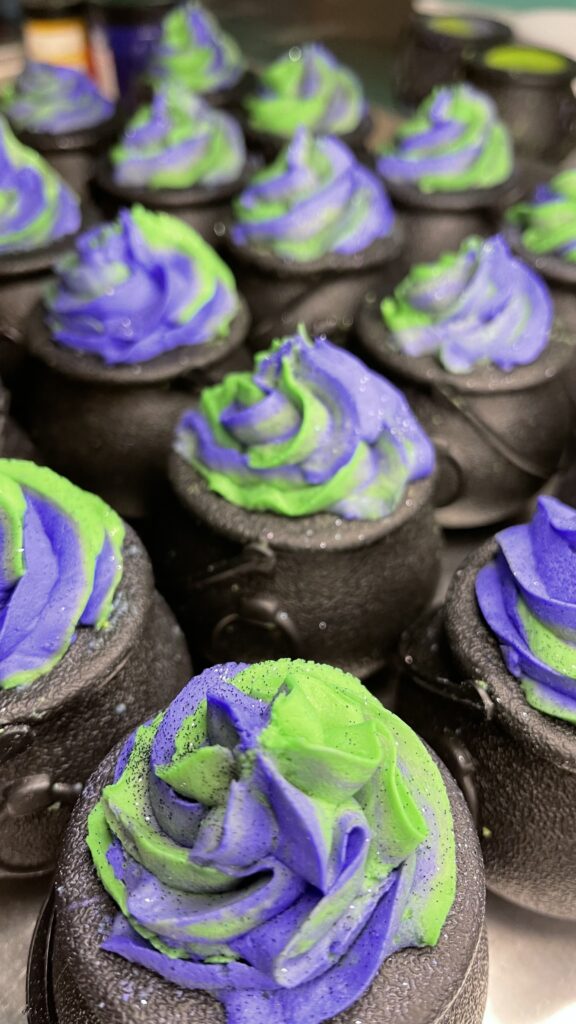 A close up of some cupcakes with purple and green frosting